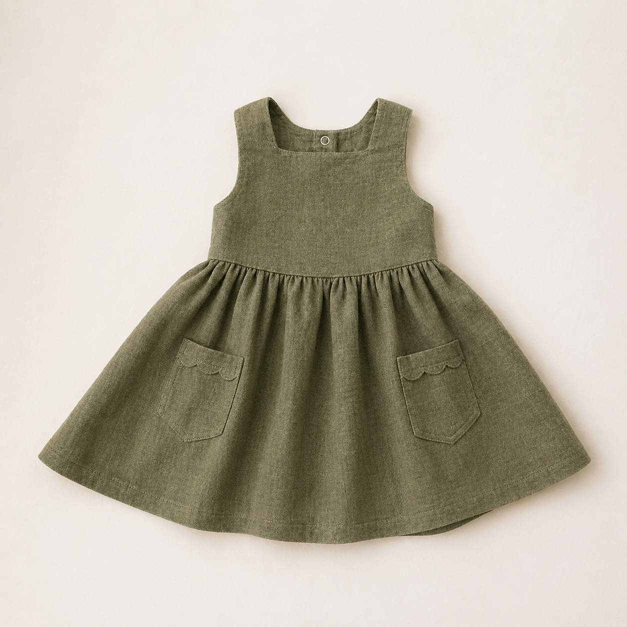 Green children's dress with pockets on a beige background